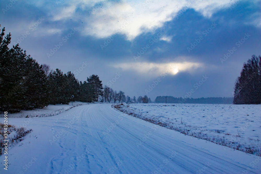 Hard winter traffic conditions with snow on road curve, snowfall and dark evening sunset