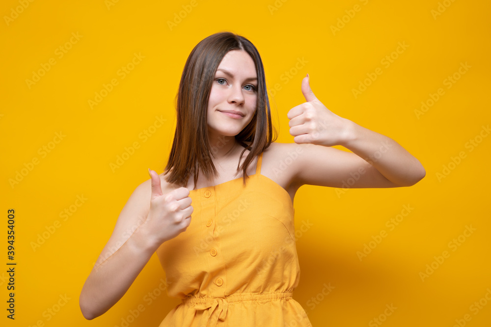Young beautiful caucasian woman in a yellow t-shirt on an isolated yellow background showing a thumb up Young beautiful caucasian woman in a yellow t-shirt on an isolated yellow background showing a thumb up