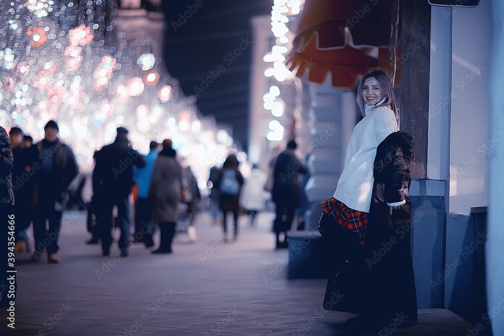Obraz premium girl christmas lights evening decorated city, a young model on the background of urban decorations and garlands, night city lights