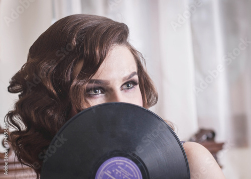 Young beautiful woman in retro style, with a vinyl record. Vintage interior.