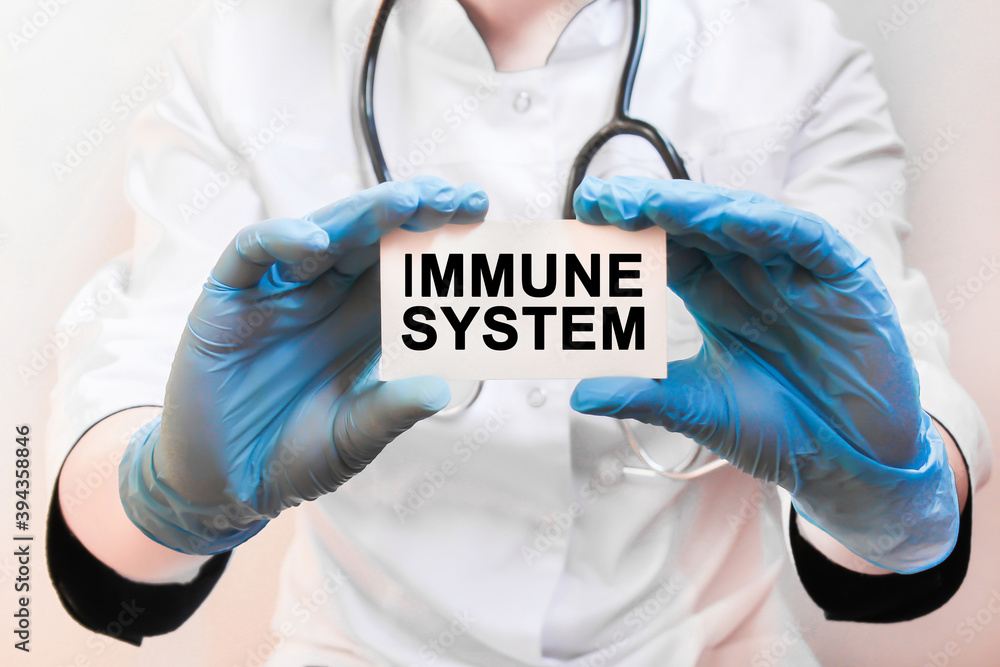 The doctor's blue - gloved hands show the word IMMUNE SYSTEM - . a gloved hand on a white background. Medical concept. the medicine The doctor's blue - gloved hands show the word IMMUNE SYSTEM - . a gloved hand on a white background. Medical concept. the medicine