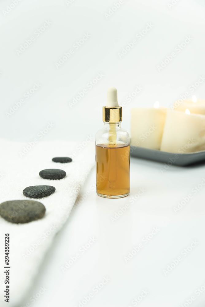 Gray zen pebble hot stones with towel and natural organic oil essence serum on massage table in beauty salon. Hot stone massage setting. Concept set of harmony, balance and meditation, spa, relax, spa Gray zen pebble hot stones with towel and natural organic oil essence serum on massage table in beauty salon. Hot stone massage setting. Concept set of harmony, balance and meditation, spa, relax, spa