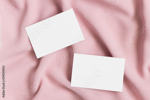 Two white business cards mockup on a soft pink textile. 85x55mm