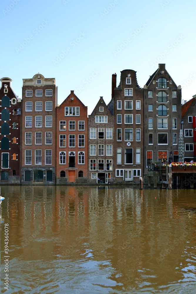 Traditional dutch houses lining Damrak canal in Amsterdam, Netherlands. Vertical photo.