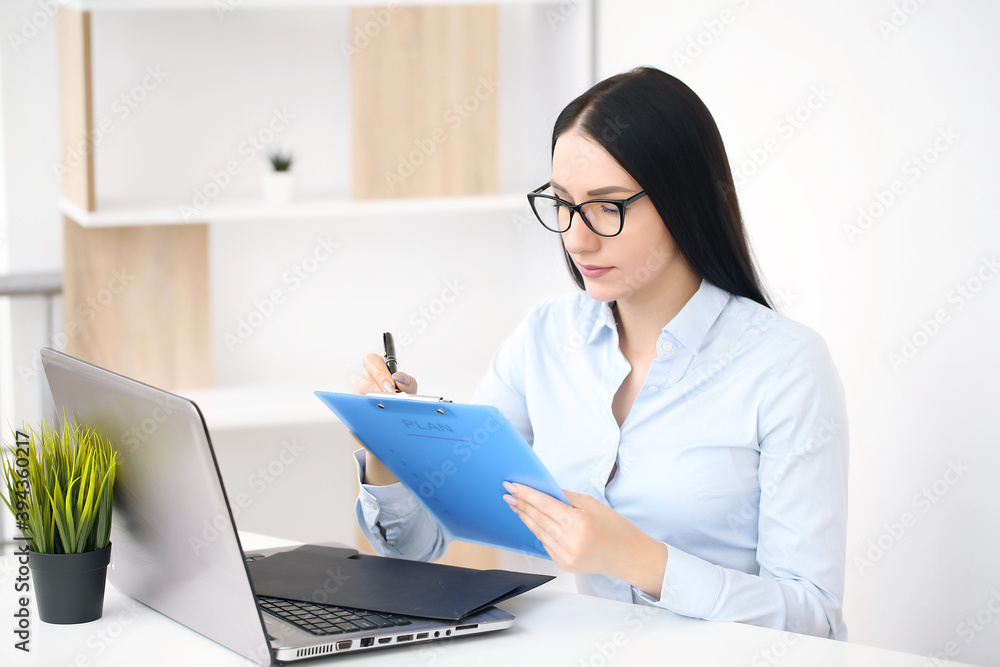 Concentrated young beautiful businesswoman working on laptop in bright modern office Concentrated young beautiful businesswoman working on laptop in bright modern office