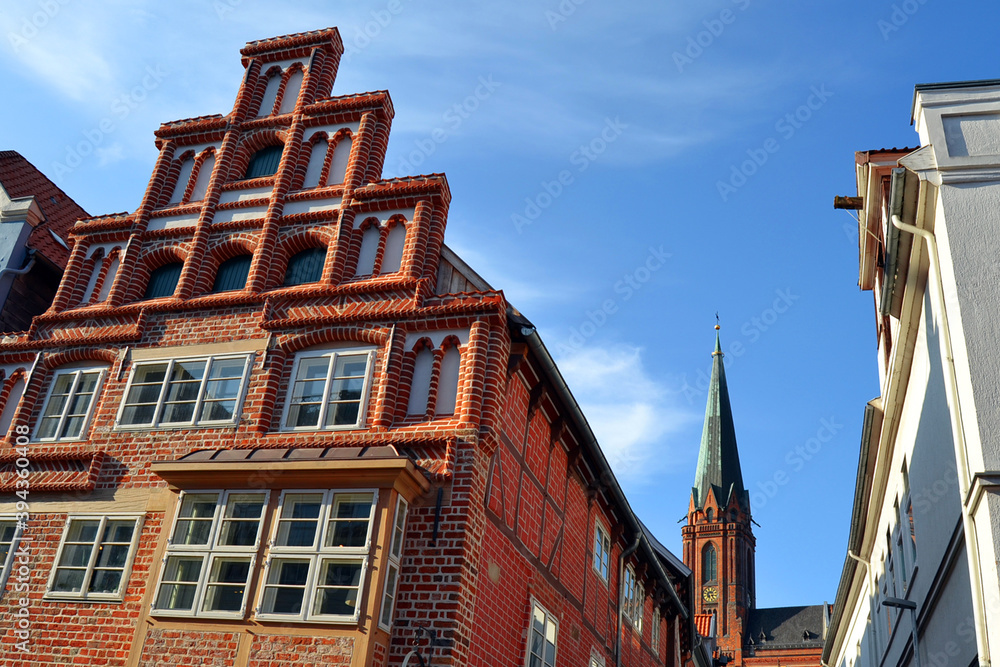 Typical old brick buildings in Luneburg, Germany, Europe. Dome of St. Nicholas Church on a background. Typical old brick buildings in Luneburg, Germany, Europe. Dome of St. Nicholas Church on a background.