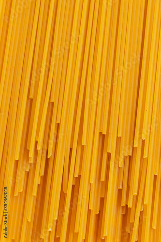 Uncooked dried spaghetti pasta on yellow background. Top view. Vertical Full Frame photo.