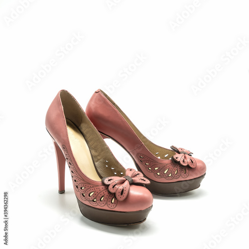 Women's shoes with high thin heels and a thick platform. Made of genuine leather in pink and brown colors. Decorated with an openwork neckline, stitching, bow. Isolated over white background.