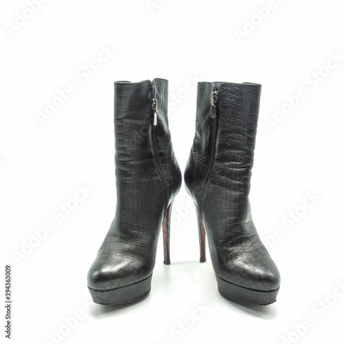 Women's black ankle boots made of genuine leather. Zipper closure, thick platform, high thin heel, red sole. Isolated over white background.