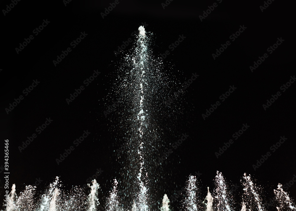 Water fountain on a dark background. Jet and spray in motion. - obrazy, fototapety, plakaty 