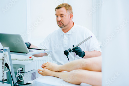 Serious medical worker with tool for rectal examination