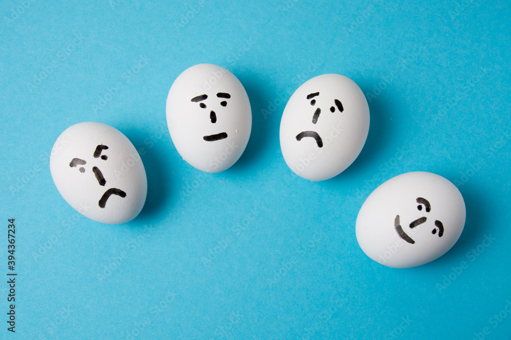 Eggs with faces and different emotions: indifference, sadness, anger and joy. Isolate on a blue background. Eggs with faces and different emotions: indifference, sadness, anger and joy. Isolate on a blue background.