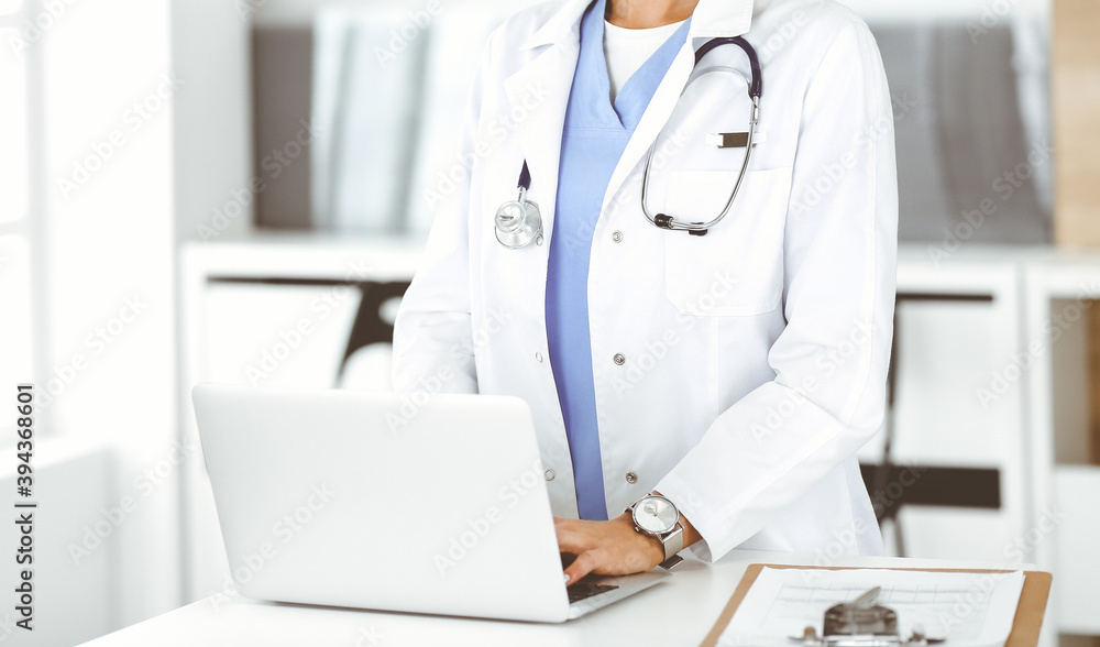 Unknown female physician using laptop computer, close-up. Woman-doctor at work in clinic. Medicine concept Unknown female physician using laptop computer, close-up. Woman-doctor at work in clinic. Medicine concept