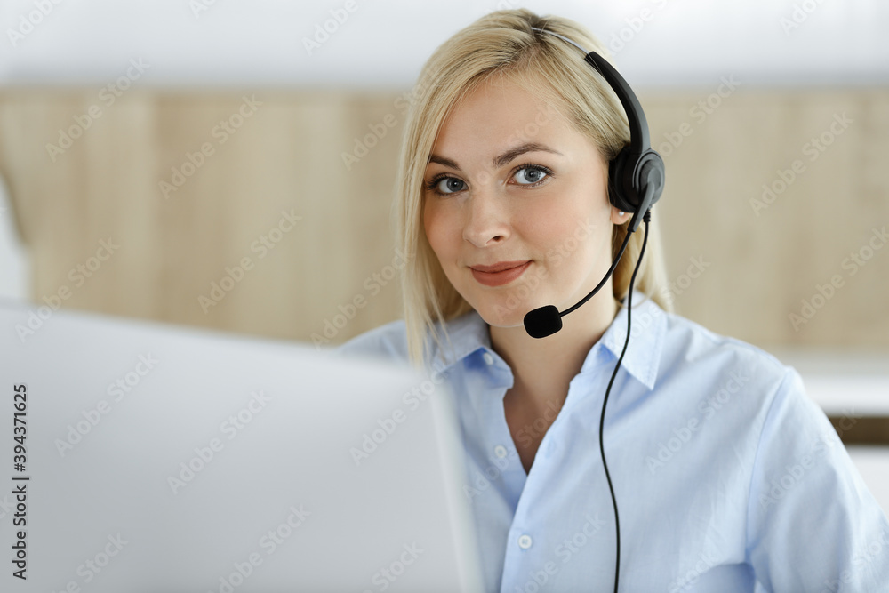 Blonde business woman sitting and communicated by headset in call center office. Concept of telesales business or home office occupation Blonde business woman sitting and communicated by headset in call center office. Concept of telesales business or home office occupation