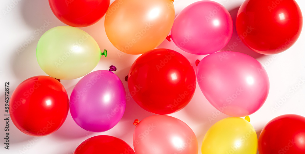 Multicolored balloons on a white background top view. Festive background with balloons. Multicolored balloons on a white background top view. Festive background with balloons.