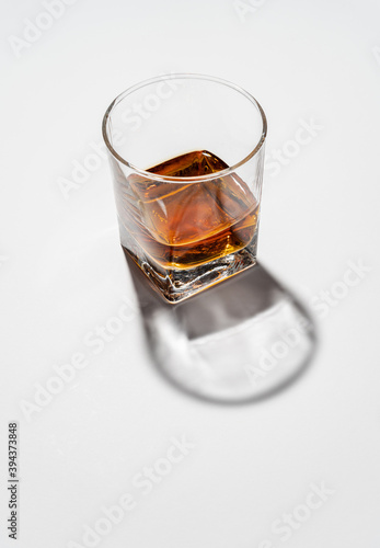 Glass of whiskey on white background with had reflections