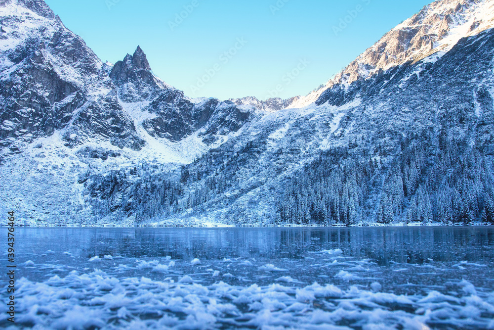 Ice winter mountain lake. Amazing frozen rocky mountains on the lakeshore. Winter background. Winter nature.