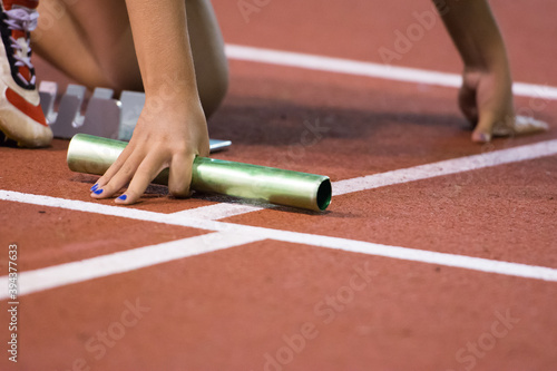Starting position for relay race on the treatmill on the stadium. Baton in hand