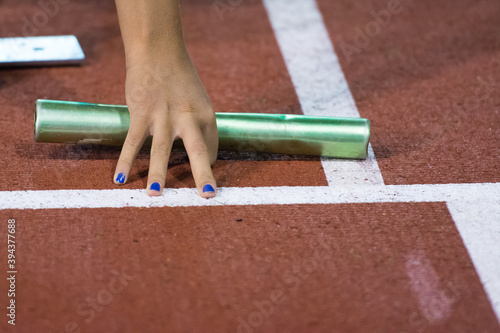 Starting position for relay race on the treatmill on the stadium. Green color baton in hand photo