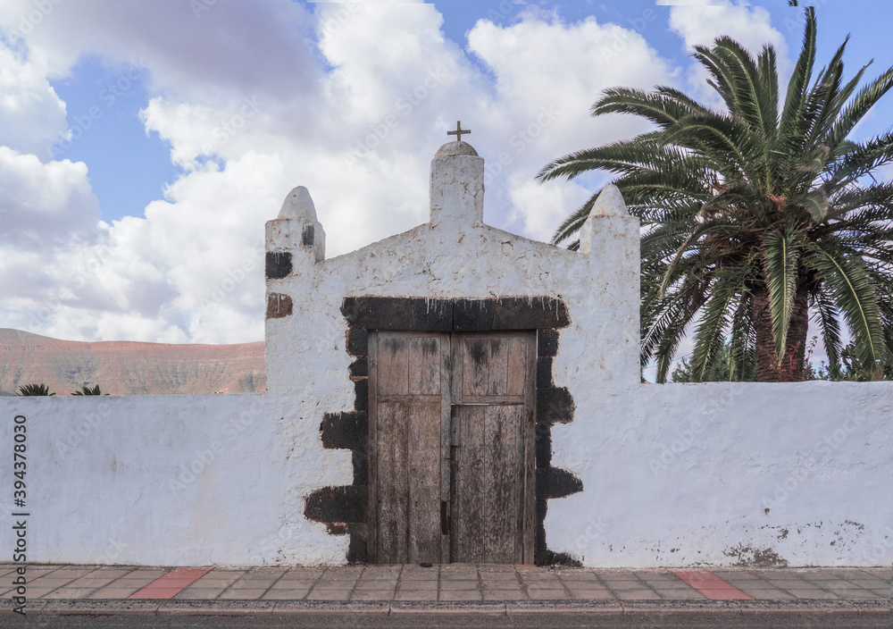 entrance of a typical white rural building with background palm trees and wooden door.Fuerteventura, Canary Islands, Spain. entrance of a typical white rural building with background palm trees and wooden door.Fuerteventura, Canary Islands, Spain.