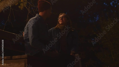 Close up of young couple sits on bentch in night park photo