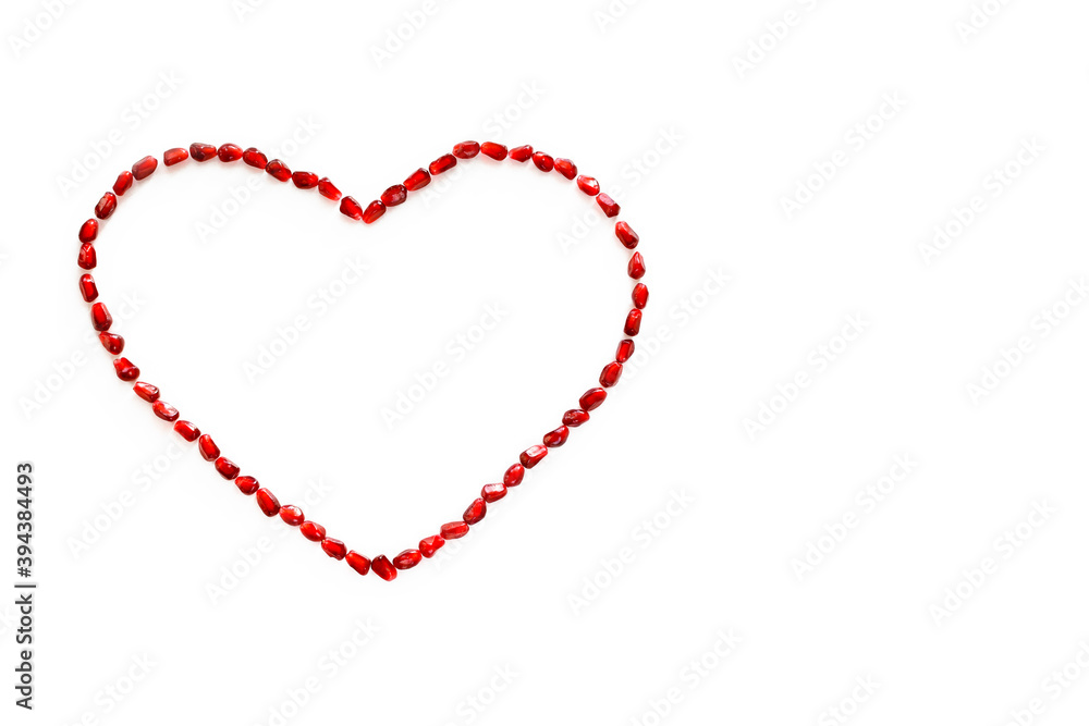 Heart symbol made from pomegranate seeds isolated on white background
