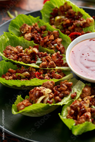 Chilli Beef Lettuce Wraps with sauce on black plate photo