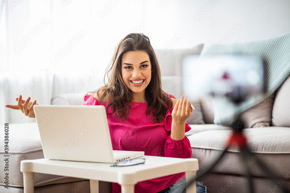 Happy girl at home speaking in front of camera for vlog. Young woman working as blogger, recording video tutorial for Internet. Young female blogger with laptop recording video at home Happy girl at home speaking in front of camera for vlog. Young woman working as blogger, recording video tutorial for Internet. Young female blogger with laptop recording video at home