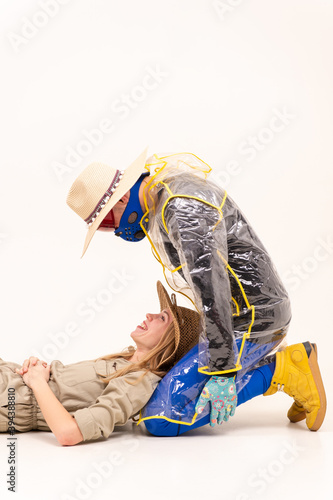Stylish man in the mask and woman in straw hats posing over white background