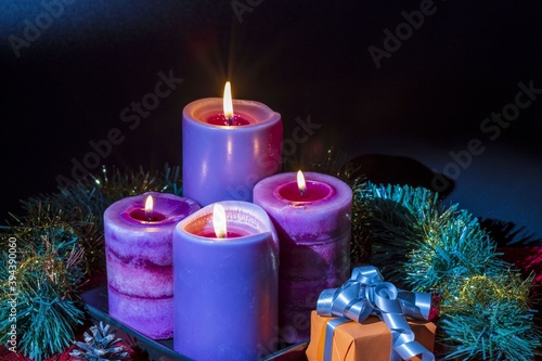 Close up view of beautiful candles and present box surrounded with green tinsel. Christmas , New Year concept.