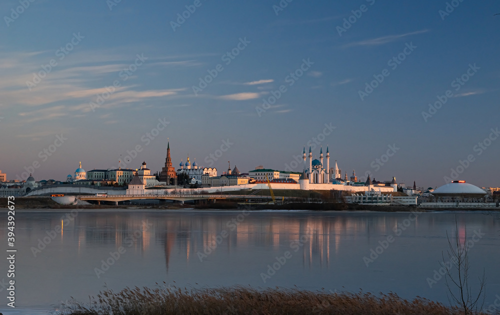The Kazan Kremlin at sunset in winter. Reflection in the ice of a frozen river. Beautiful view of the city