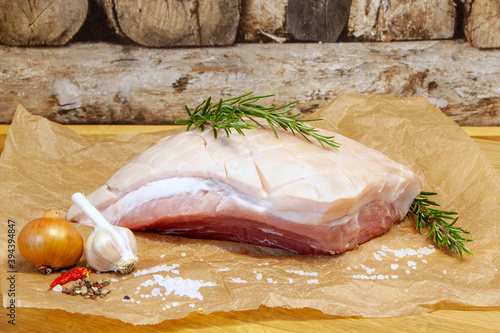 Raw Pork belly with sea salt, onion, garlic and herbs, rosemary. Roast salted pork, Bavarian crust roast. preparation for grooved pork celebration dinner, Christmas ham, Festival food. 