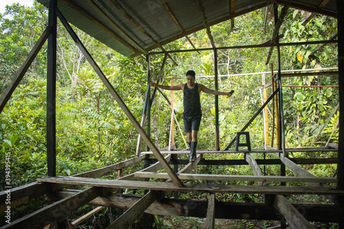 Hombre joven haciendo equilibrio en una construcción de una casa en medio de la naturaleza
