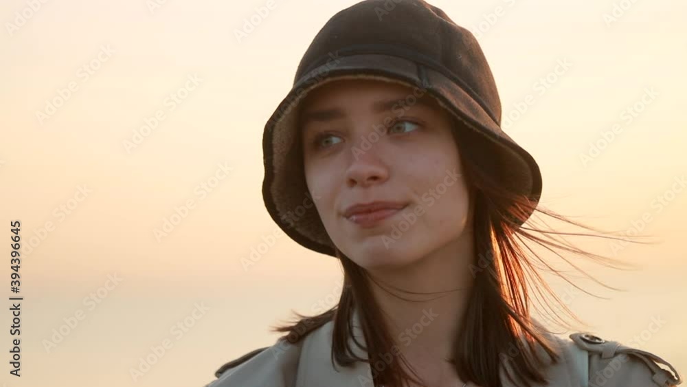 Portrait of beautiful woman poses for camera on background sky outdoors spbi. Face view of attractive Young female model posing with happy smile while standing on beach during golden sunset. One Portrait of beautiful woman poses for camera on background sky outdoors spbi. Face view of attractive Young female model posing with happy smile while standing on beach during golden sunset. One