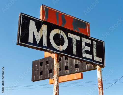 Weathered vintage motel sign against blue sky. © Noel