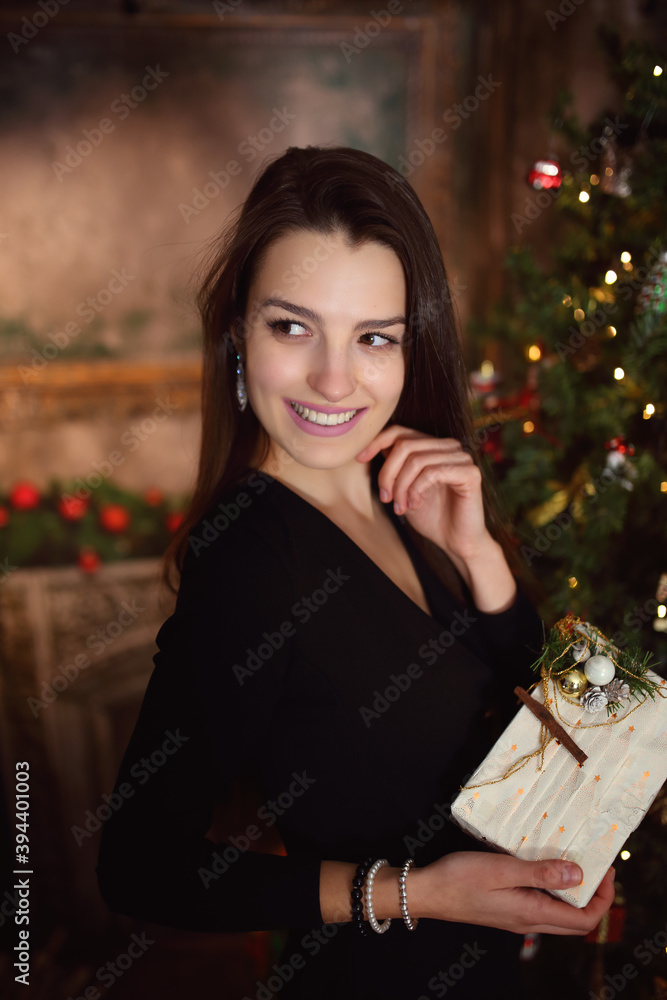 young brunette in a festive mood in a black dress by the Christmas tree young brunette in a festive mood in a black dress by the Christmas tree