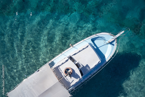 Top view of boat on clear turquoise water. Empty boat floating on crystal ocean water. View from above.
