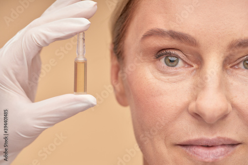 Papier peint Beautician in a glove holding an ampoule with hyaluronic acid