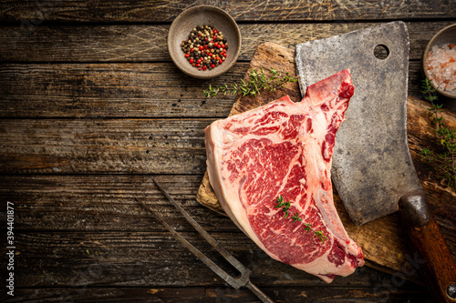 Raw fresh meat T-bone beef Steak and butcher knife on wooden background, top view