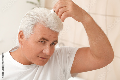 Senior man using serum for ...