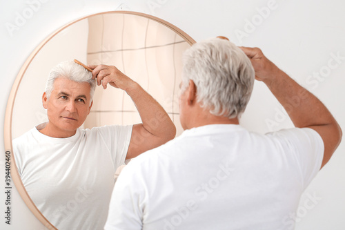 Senior man combing his hair...
