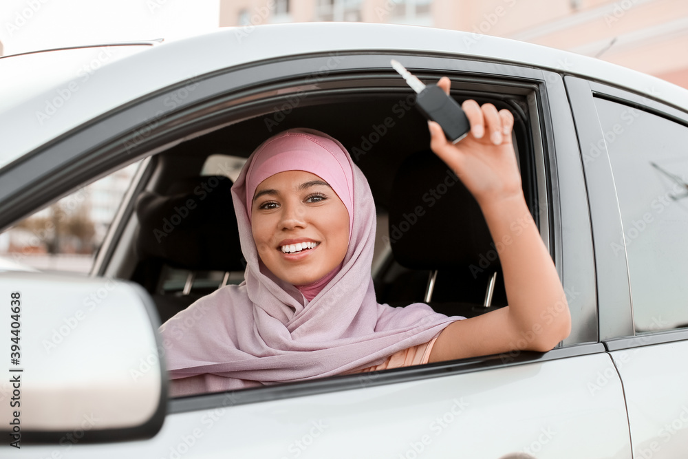 Young Muslim woman with key sitting in new car Young Muslim woman with key sitting in new car