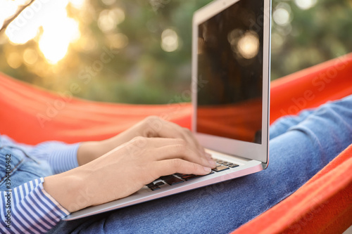 Fototapeta Naklejka Na Ścianę i Meble -  Beautiful young woman with laptop relaxing in hammock outdoors, closeup