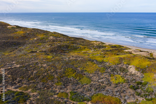 Waves from the Pacific Ocean wash onto an empty beach and sand dunes in Morro Bay, California. This coastal part of Central California is known for its beautiful natural scenery.