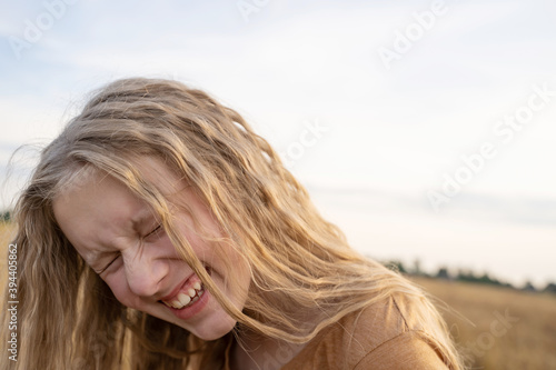 portrait of a  smiled girl with curly  blond hair  of twelve years old outdoor