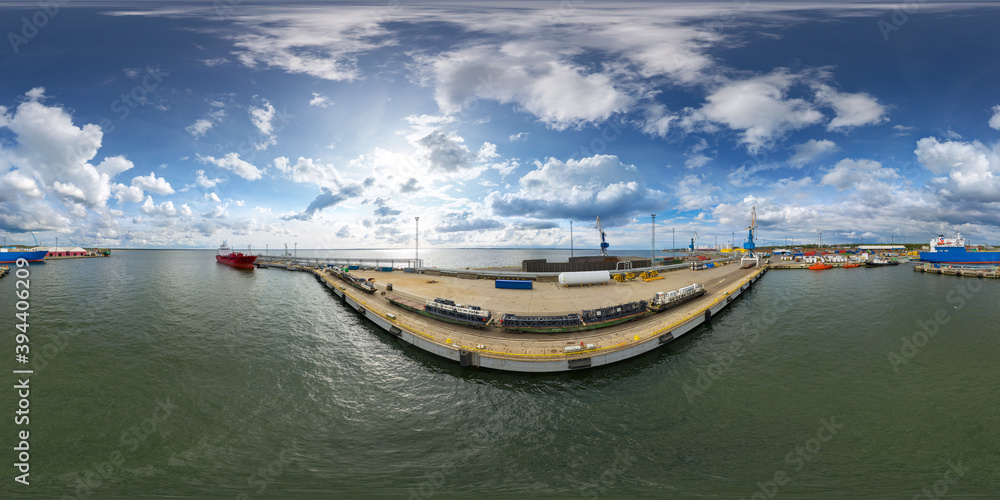 An aerial drone view of the industrial port of Paldiski in the Baltic Sea, Estonia. There is a ships under load in the harbor. 360 degrees panorama
