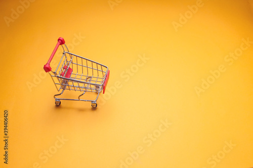 Trolley on yellow background. Shopping concept