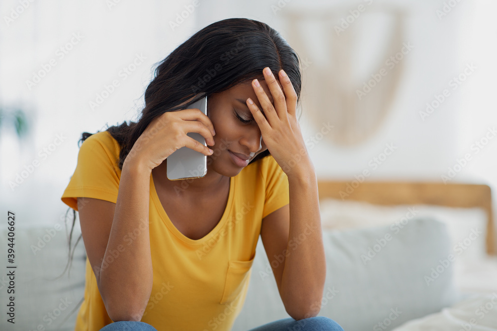 Frustrated black woman having unpleasant conversation on cellphone at home, free space Frustrated black woman having unpleasant conversation on cellphone at home, free space