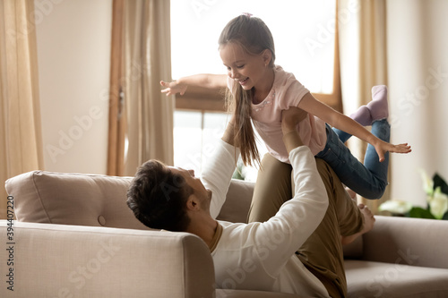 Billede på lærred Preschool daughter play with daddy at home, happy father lifts up on arms little