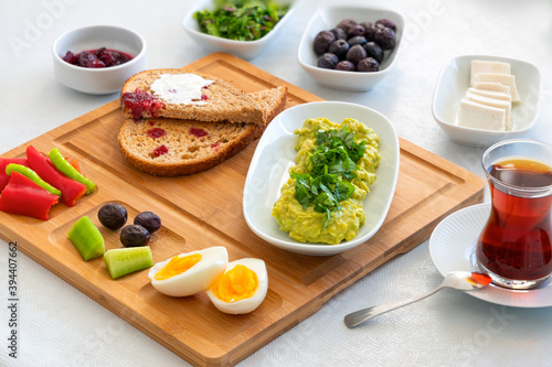 Healthy and delicious Mediterranean breakfast. Boiled egg, avocado paste, olive, jam toast and tee